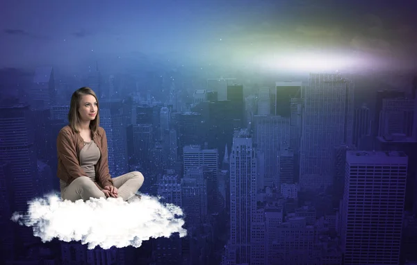Vrouw zitten op wolk boven de stad — Stockfoto