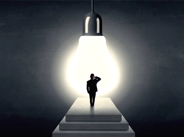 Man standing on a step in front of a huge light bulb — Stock Photo, Image