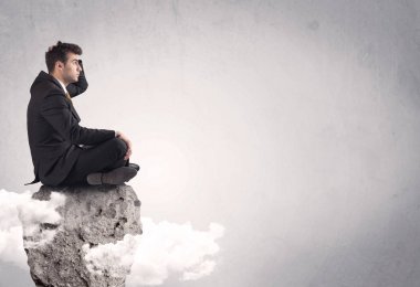 Ofis çalışanı kayanın tepesinde oturuyor.