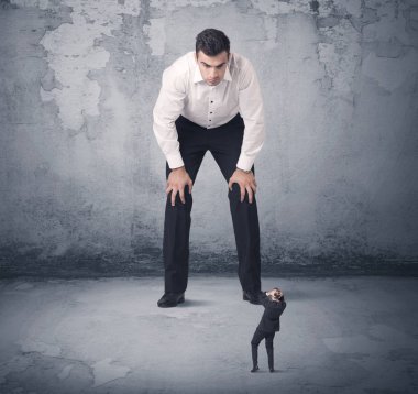 Büyük işletme zorbası küçük iş arkadaşına bakıyor.