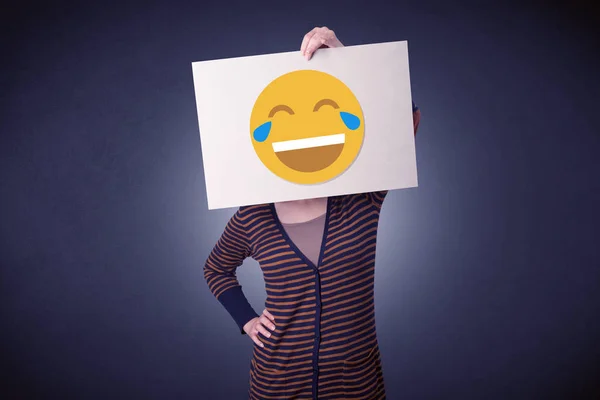 Woman holding paper with laughing emoticon — Stock Photo, Image