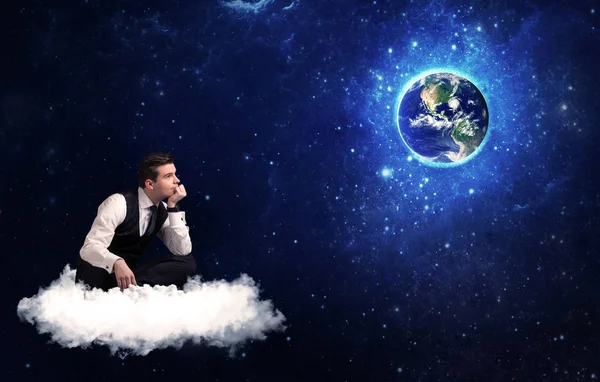 Человек, сидящий на облаке, глядя на планету Земля — стоковое фото