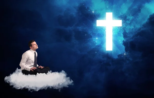 Man sitter på cloud lokking på ett kors — Stockfoto