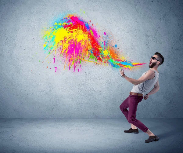 Hipster guy shouting colorful paint on wall — Stock Photo, Image