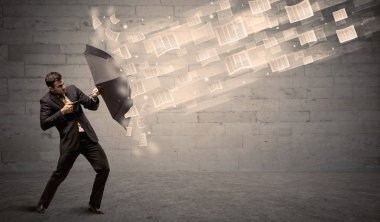 İş adamı ile şemsiye kağıtları rüzgara karşı koruma