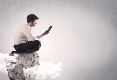 Ofis çalışanı kayanın tepesinde oturuyor.