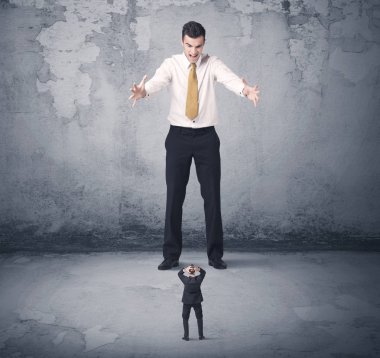 Büyük işletme zorbası küçük iş arkadaşına bakıyor.