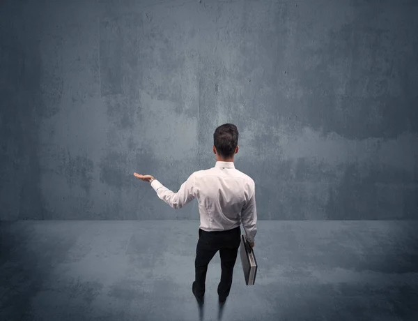 Businessman standing in front of urban wall — Stock Photo, Image