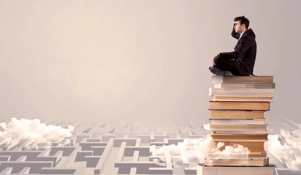 Geschäftsmann sitzt im Labyrinth auf Büchern — Stockfoto
