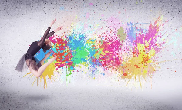 Modern street dancer jumping with colorful paint splashes