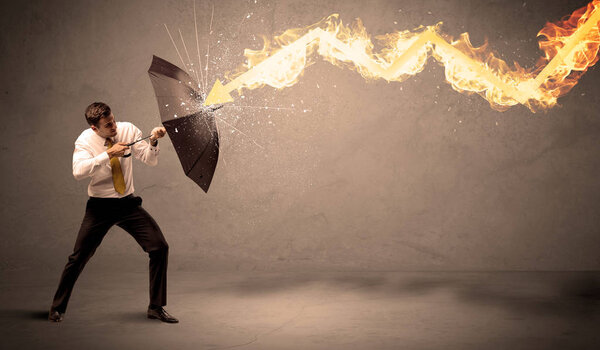 Business man defending himself from a fire arrow with an umbrell