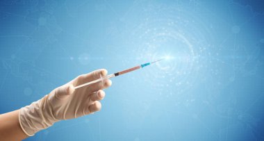 Kadın doktor elinde şırınga tutuyor.