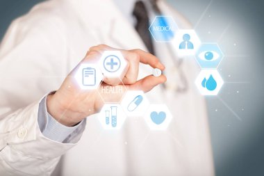 Beyazlı bir doktor elinde hap tutuyor.