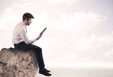 İş adamı taşın üstünde oturuyor.