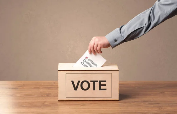 Primer plano de la mano masculina poniendo el voto en una urna —  Fotos de Stock