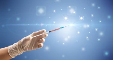 Kadın doktor elinde şırınga tutuyor.