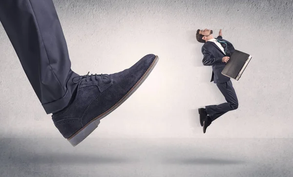 Small businessman kicked by big shoe — Stock Photo, Image