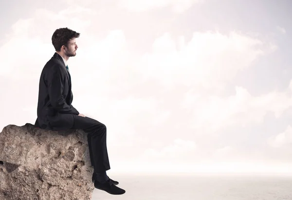 Business man sitting on stone edge — Stock Photo, Image