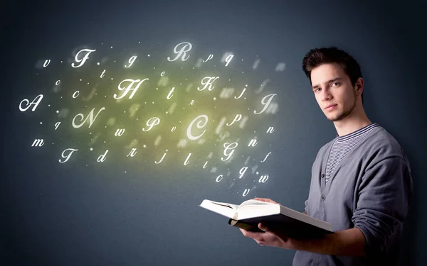 Jovem segurando livro com letras — Fotografia de Stock