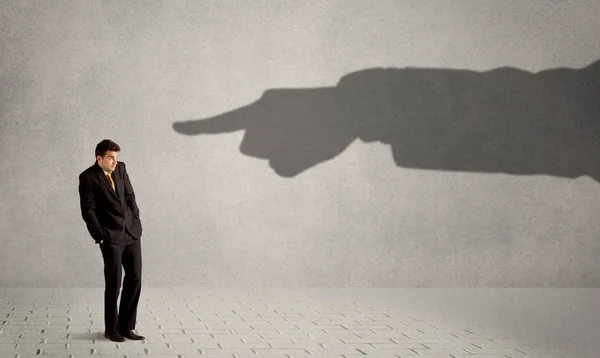 Business person looking at huge shadow hand pointing at him conc — Stock Photo, Image