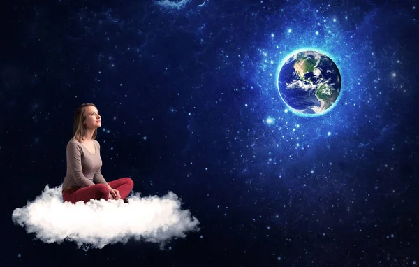 Femme assise sur un nuage regardant la planète Terre — Photo