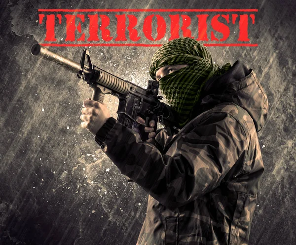 Dangerous masked and armed man with terrorist sign on grungy bac