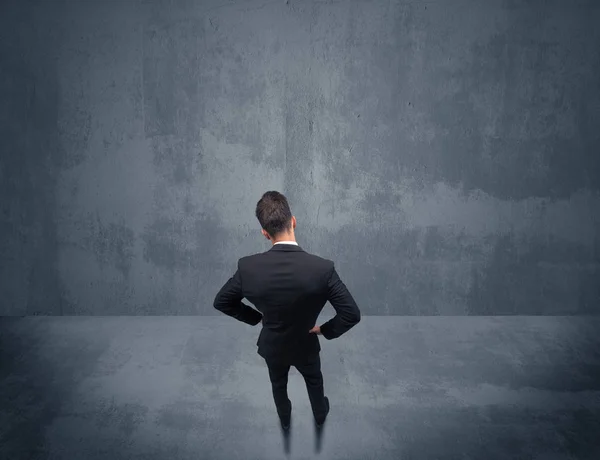 Businessman standing in front of urban wall — Stock Photo, Image