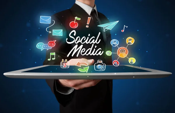 Businessman holding tablet with social media graphics