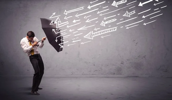 Business man standing with umbrella and drawn arrows hitting him — Stock Photo, Image