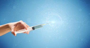 Kadın doktor elinde şırınga tutuyor.