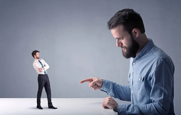 Joven hombre de negocios luchando con empresario en miniatura —  Fotos de Stock