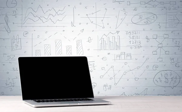 壁にビジネスチャートと机の上のノートパソコン — ストック写真
