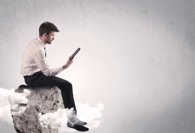 Ofis çalışanı kayanın tepesinde oturuyor.