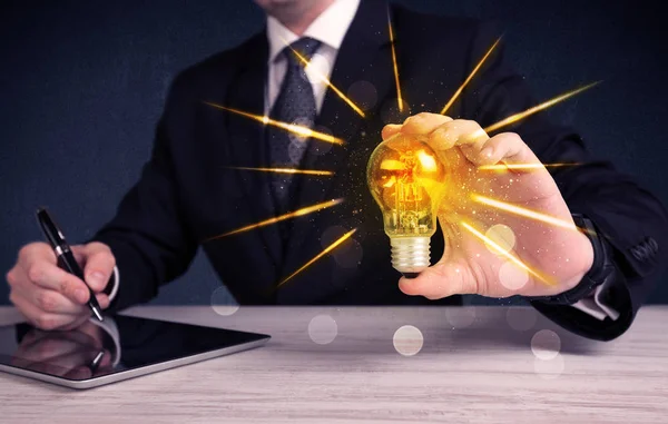 Business person holding an electric light bulb — Stock Photo, Image