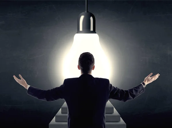 Man standing on a step in front of a huge light bulb — Stock Photo, Image