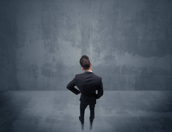 Businessman standing in front of urban wall — Stock Photo, Image