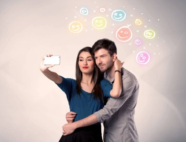 Mutlu çift gülen yüzle selfie çekiyor.