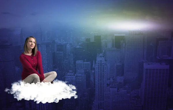 Женщина, сидящая на облаке над городом — стоковое фото