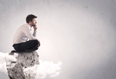 Ofis çalışanı kayanın tepesinde oturuyor.