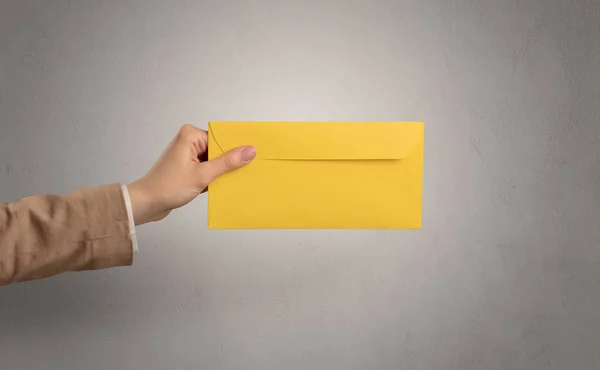 Hand holding envelope with empty wall background — Stock Photo, Image