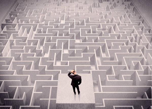 Бизнесмен смотрит на лабиринт сверху
