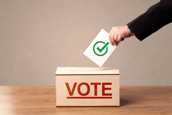 Fechar a mão masculina colocando voto em uma urna — Fotografia de Stock