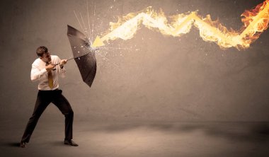 İş adamı kendini bir umbrell ile bir yangın oka savunmak