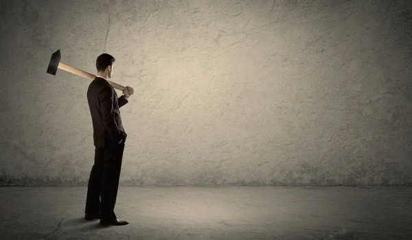 Ділова людина стоїть перед гранжевою стіною з молотком — стокове фото