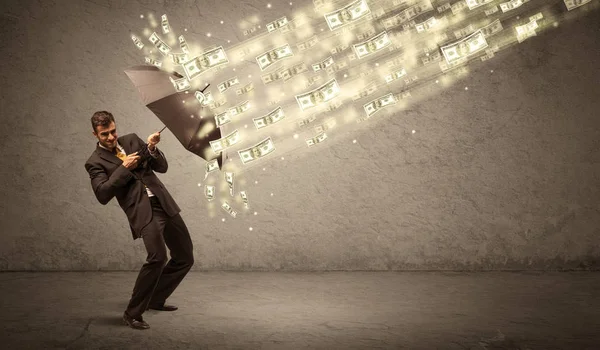 Hombre de negocios sosteniendo paraguas contra concepto de lluvia dólar — Foto de Stock