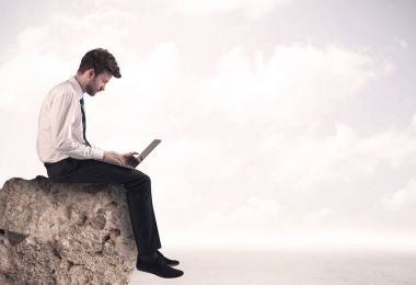 İş adamı taşın üstünde oturuyor.