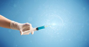 Kadın doktor elinde şırınga tutuyor.