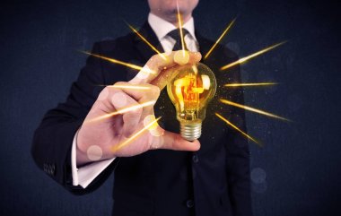 bir elektrik ampulü tutan iş kişi