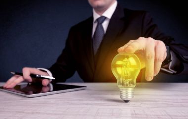 parlak sarı ampul tutan takım elbiseli adam