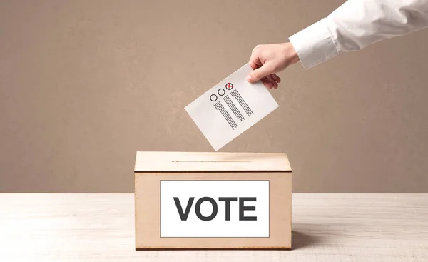 Close up of male hand putting vote into a ballot box — Stock Photo, Image